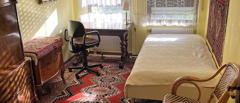 A room with a bed, a desk, a chair, a dresser, and a patterned rug.