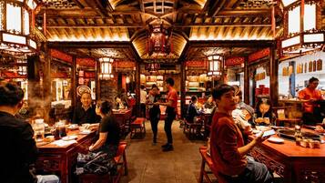 A traditional restaurant interior with wooden beams, red lanterns, and patrons dining.