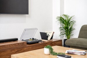 A modern living room with a wooden coffee table, a vinyl record player, a plant, and a couch. - The Richmond Grand | Near MCG + 3 Free Car Spaces (Richmond)
