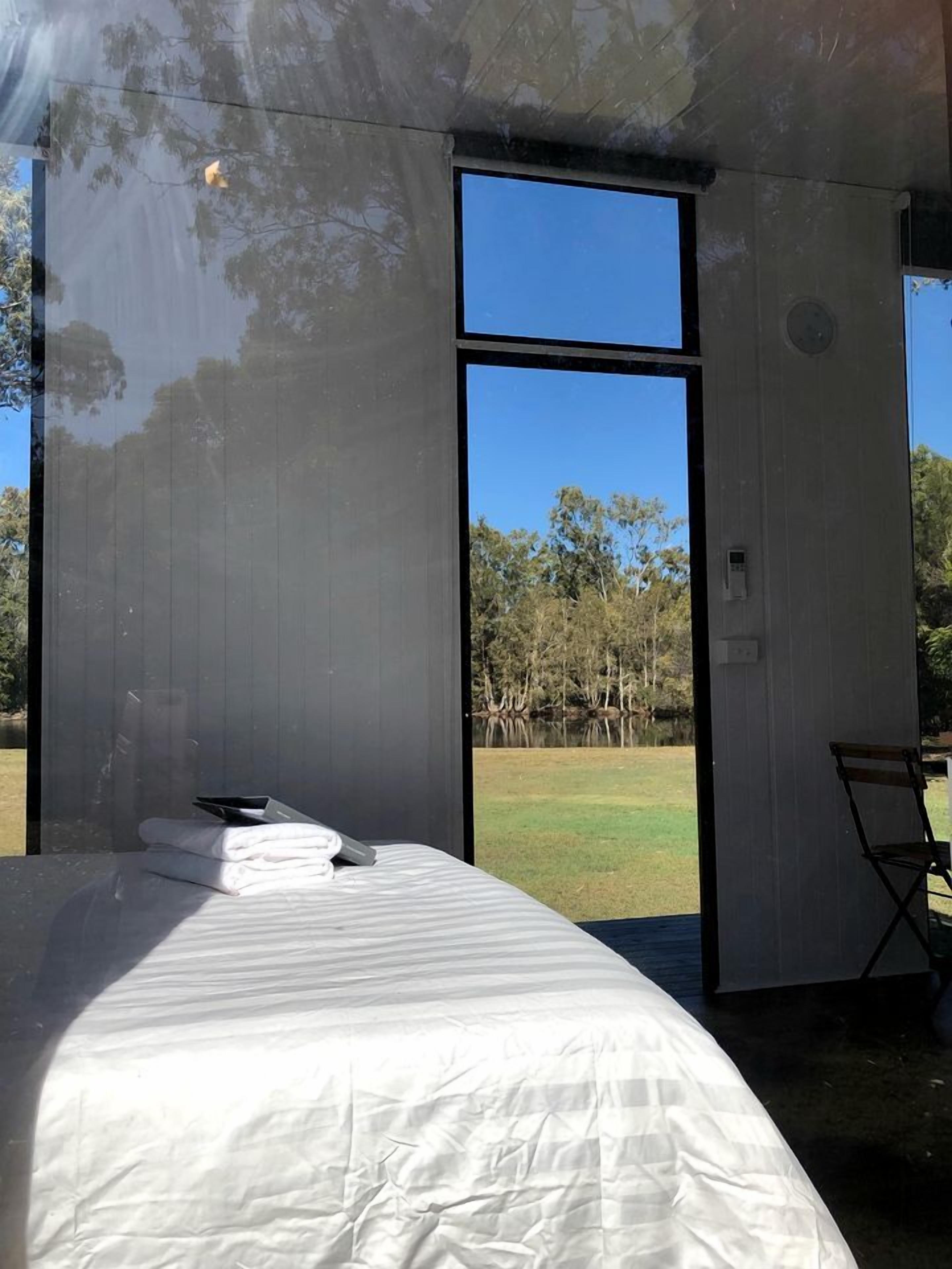 A bedroom with a bed, a chair, and a view of a natural landscape.