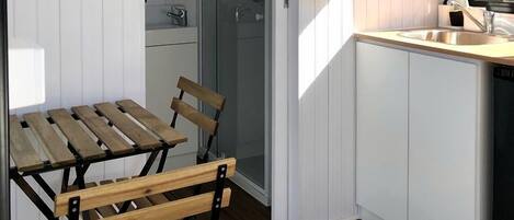 A compact kitchen with a wooden table and chairs, a sink, and a window.