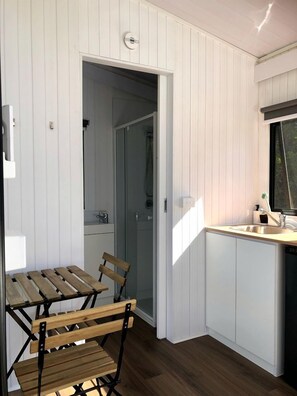 Una cocina compacta con una mesa y sillas de madera, un lavabo y un ventanal.