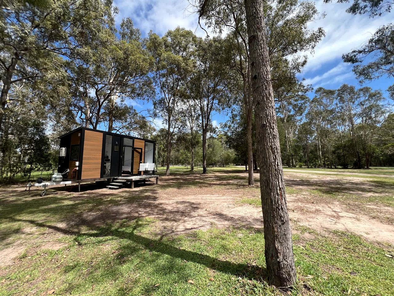 Una casa móvil con terraza, ubicada en un área verde con árboles.