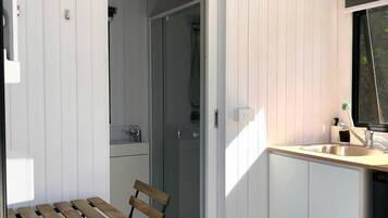A compact kitchen with a wooden table and chairs, a sink, and a window.