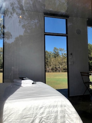 Un dormitorio con cama, una silla y vista a un paisaje natural.