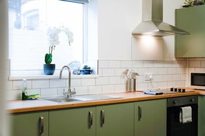 A kitchen with a window, sink, stove, and green cabinets. - Queen Street 5BR Stay 10 Guests by Stay With Us (Redcar)