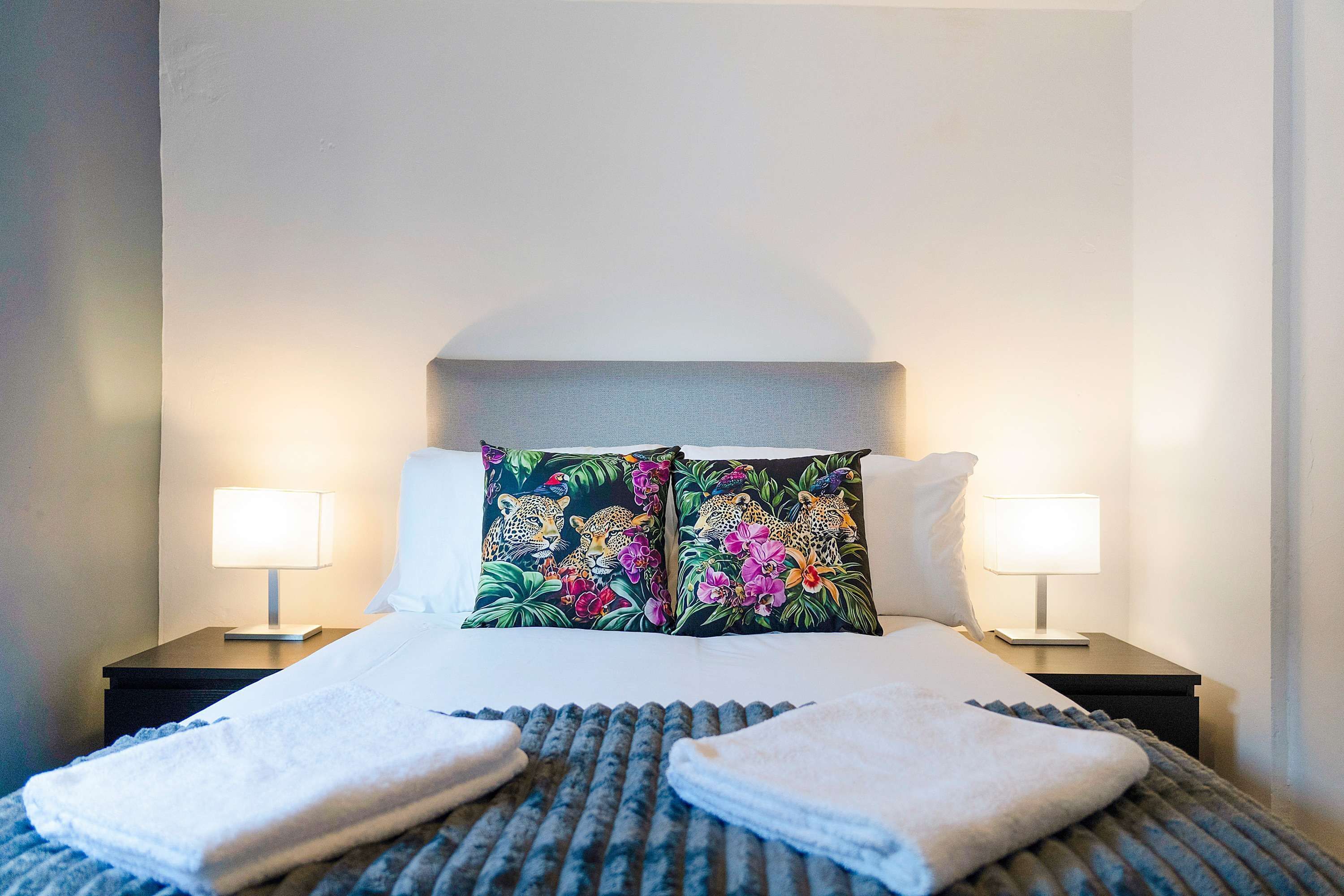 Ein Hotelzimmer mit einem Bett, zwei Nachttischlampen und einem Kopfteil.