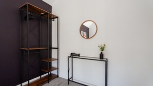 Et værelse med et klædeskab, et rundt spejl og et lille bord med en plante.