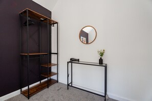 Ein Zimmer mit Kleiderschrank, rundem Spiegel und einem kleinen Tisch mit Pflanze.