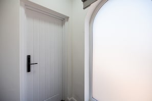 Eine weiße Tür mit schwarzem Griff und einem Fenster zur Rechten.