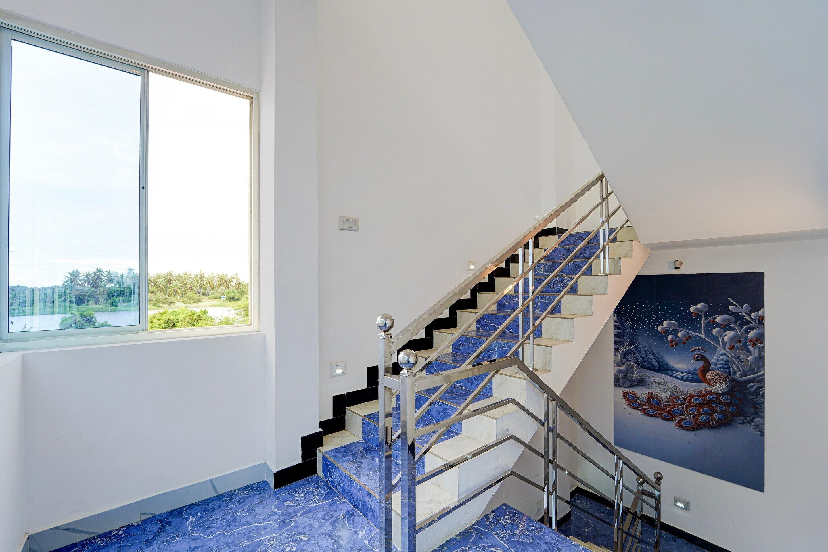 Um interior moderno com uma escada, uma janela grande e uma pintura.