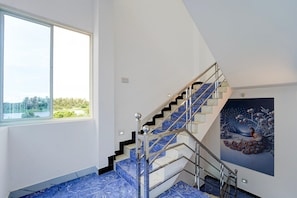 A modern interior with a staircase, a large window, and a painting.