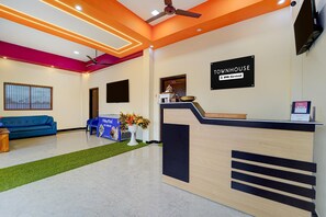 A reception area with a modern design, including a reception desk, a blue sofa, and a decorative plant.