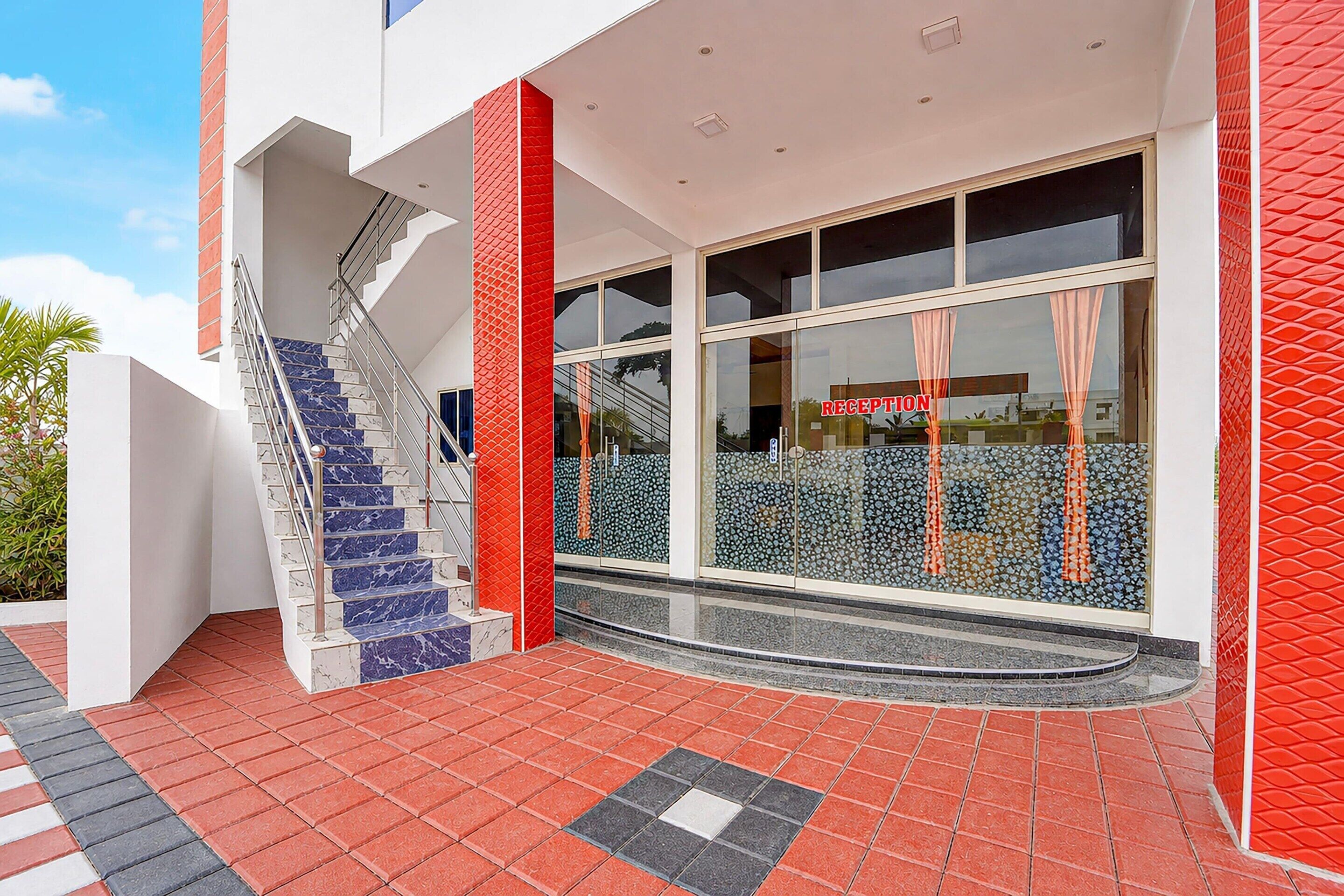 A modern building with a reception area, a staircase with marble steps, and a red and white facade.