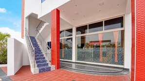 Un edificio moderno con área de recepción, una escalera de peldaños de mármol y fachada en rojo y blanco.