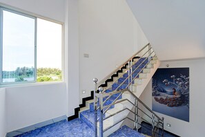 A modern interior with a staircase, a large window, and a painting. - Classic Sonia Mahi Inn (Nagercoil)