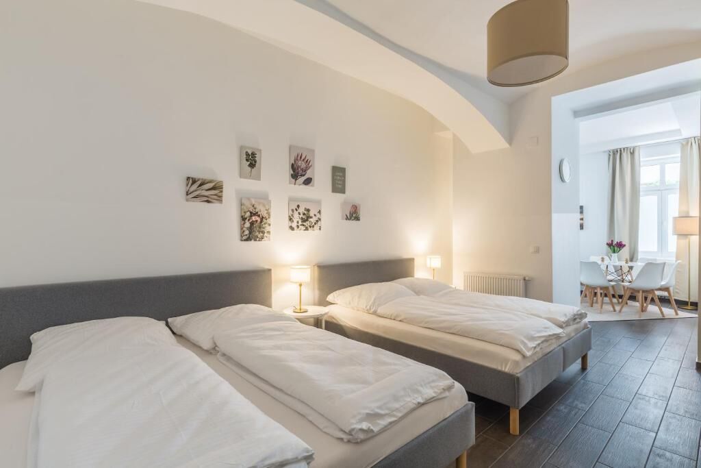 A hotel room with two beds, a dining area, and artwork on the walls.