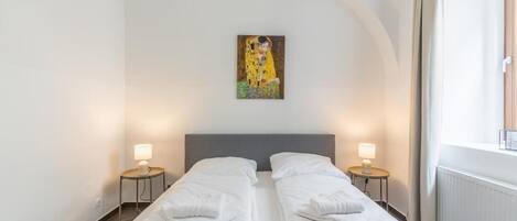 Una habitació d'hotel amb dos llits, un quadre a la paret i una finestra amb cortines.