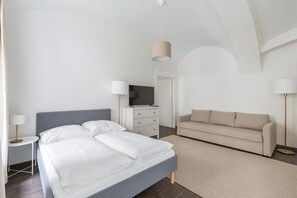Un dormitorio moderno con cama, sofá, cómoda y televisor.
