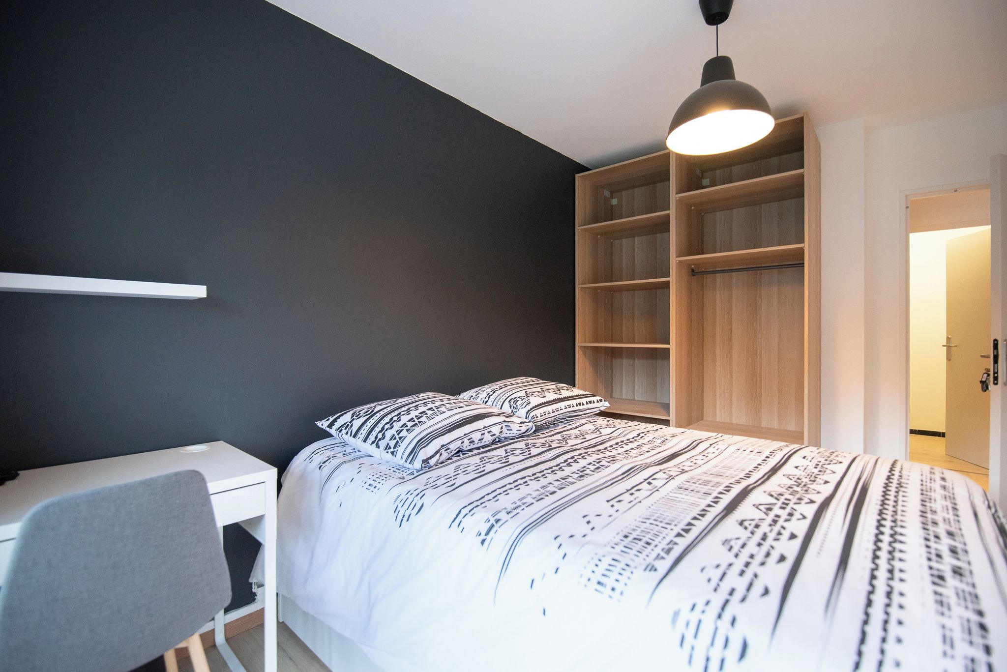 Un dormitorio con cama, escritorio y armario.