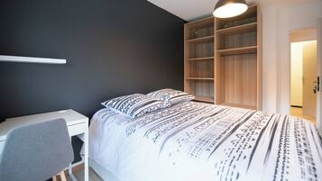 Un dormitorio con cama, escritorio y armario.