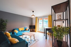 A modern living room with a sofa, coffee table, and a dining area with chairs. - Les chambres du Vercors (Fontaine)