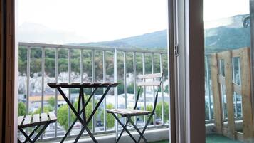 Un balcón con una mesa y sillas, con vistas a un paisaje montañoso.
