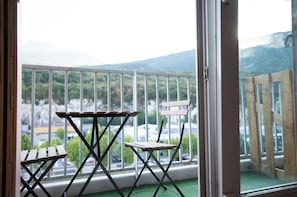 Un balcón con una mesa y sillas, con vistas a un paisaje montañoso.