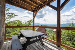 A wooden deck with a table and benches, overlooking a mountainous landscape. - Amazing View Lodge is a spectacular seven-bedroom cabin (Sevierville)