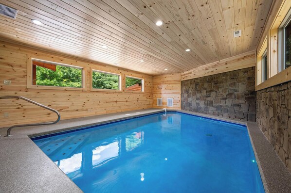An indoor swimming pool with wooden walls and a stone accent wall. - Amazing View Lodge is a spectacular seven-bedroom cabin (Sevierville)