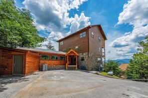 A two-story log cabin with a stone foundation, a wooden porch, and a clear sky. - Amazing View Lodge is a spectacular seven-bedroom cabin (Sevierville)