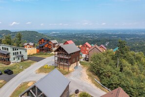 A residential area with a mix of modern and traditional houses, a paved road, and a view of distant hills. - One Bedroom 2 Story Log Cabin with Panoramic Views! (Sevierville)