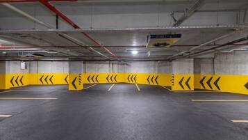 Un estacionamiento vacío con barreras de seguridad amarillas y flechas direccionales en el suelo.