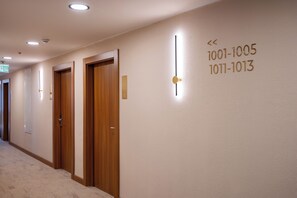 A hotel hallway with wooden doors, numbered room signs, and a carpeted floor.