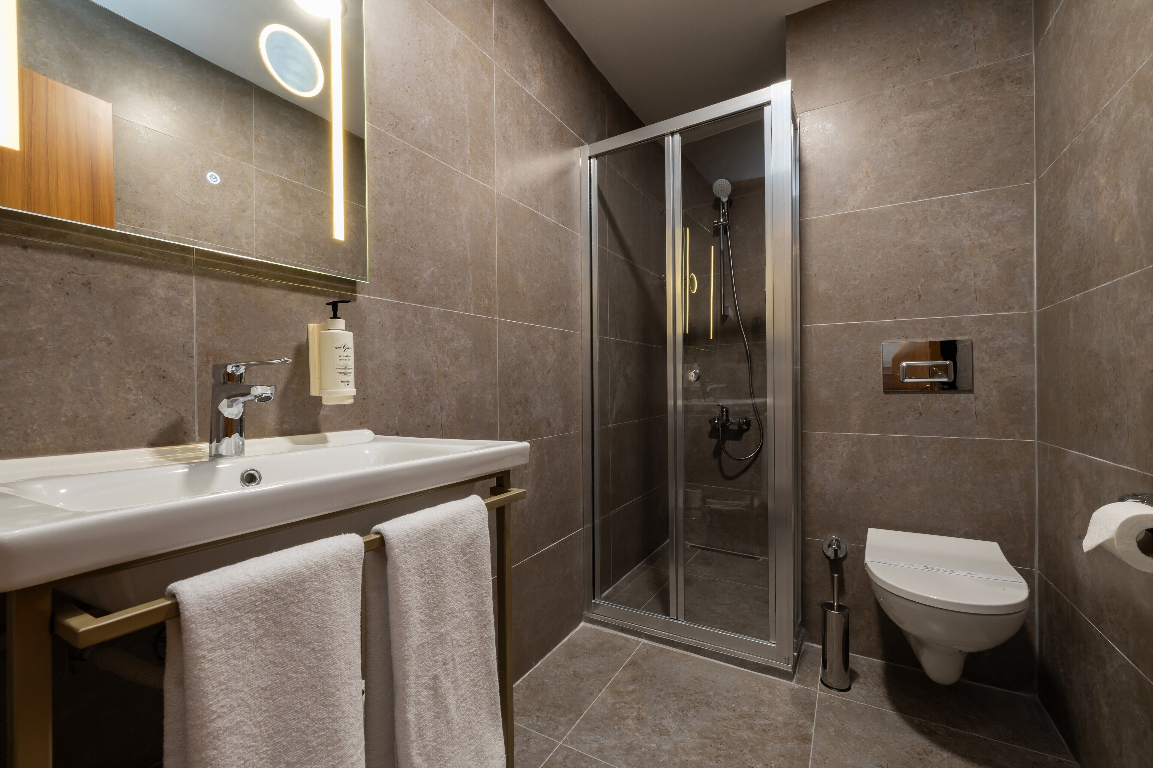 Ein modernes Badezimmer mit einer gläsernen Duschkabine, einem weißen Waschbecken und einer Toilette.