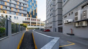Una calle urbana moderna con un camino estrecho, coches aparcados y edificios con balcones.