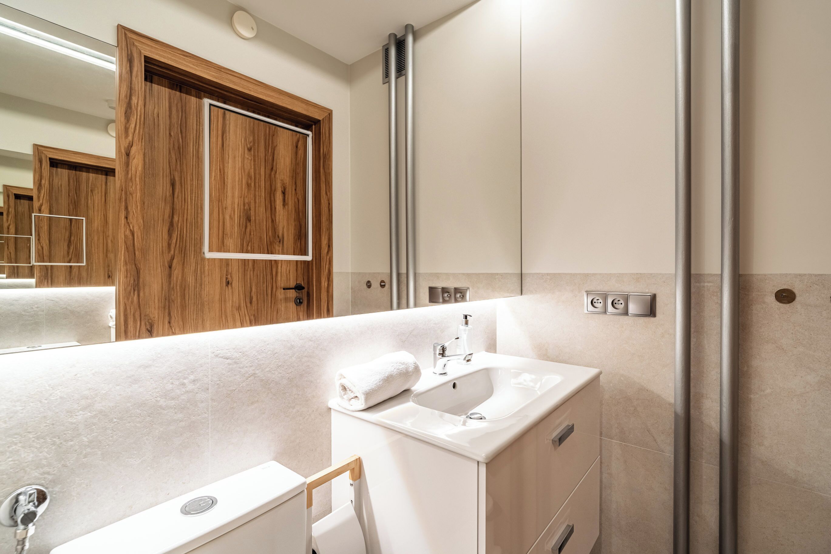 A modern bathroom with a white sink, a mirror, and a shower area.