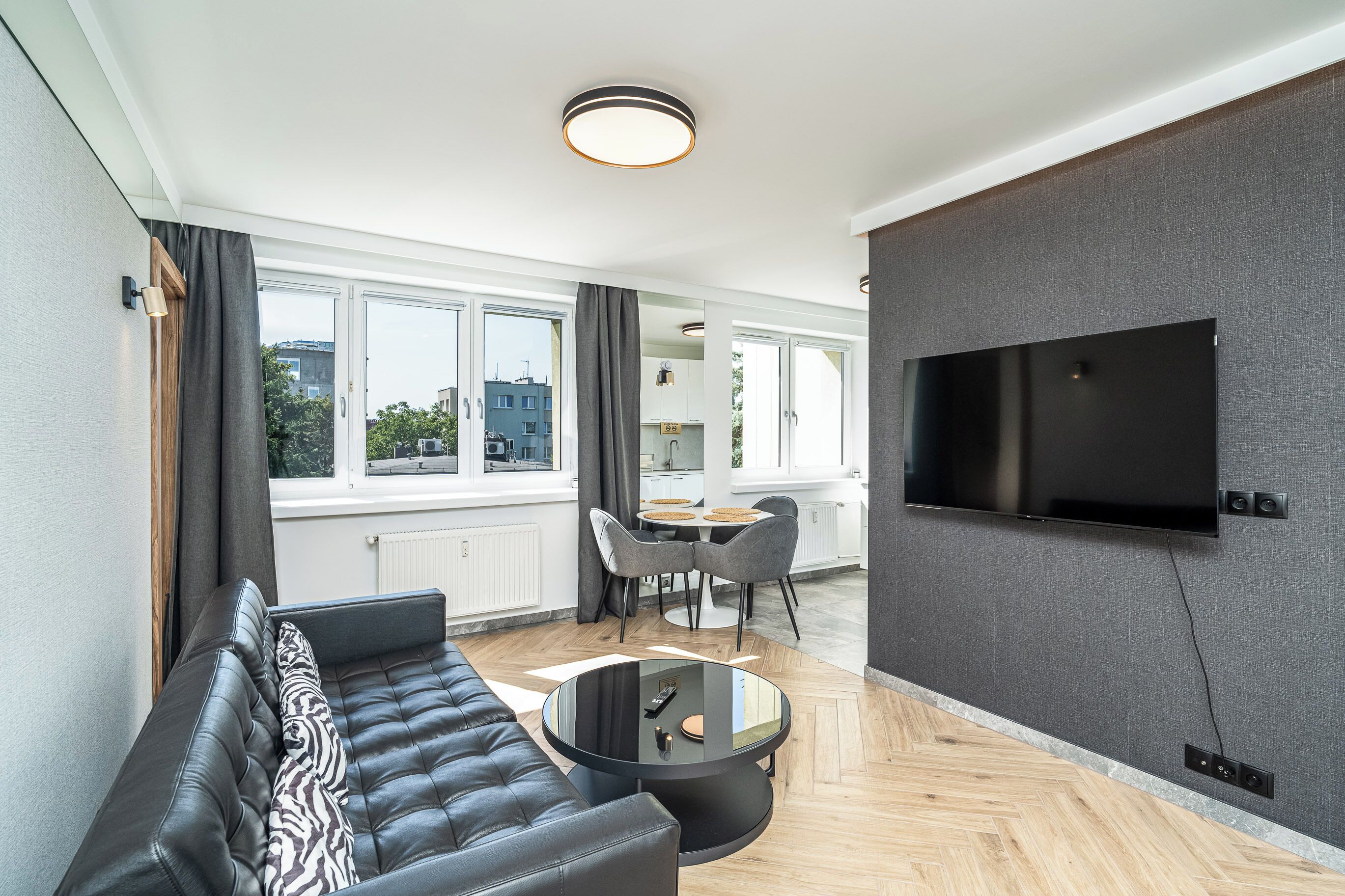 Una sala moderna con un sofá, una mesa de centro y un televisor montado en la pared.