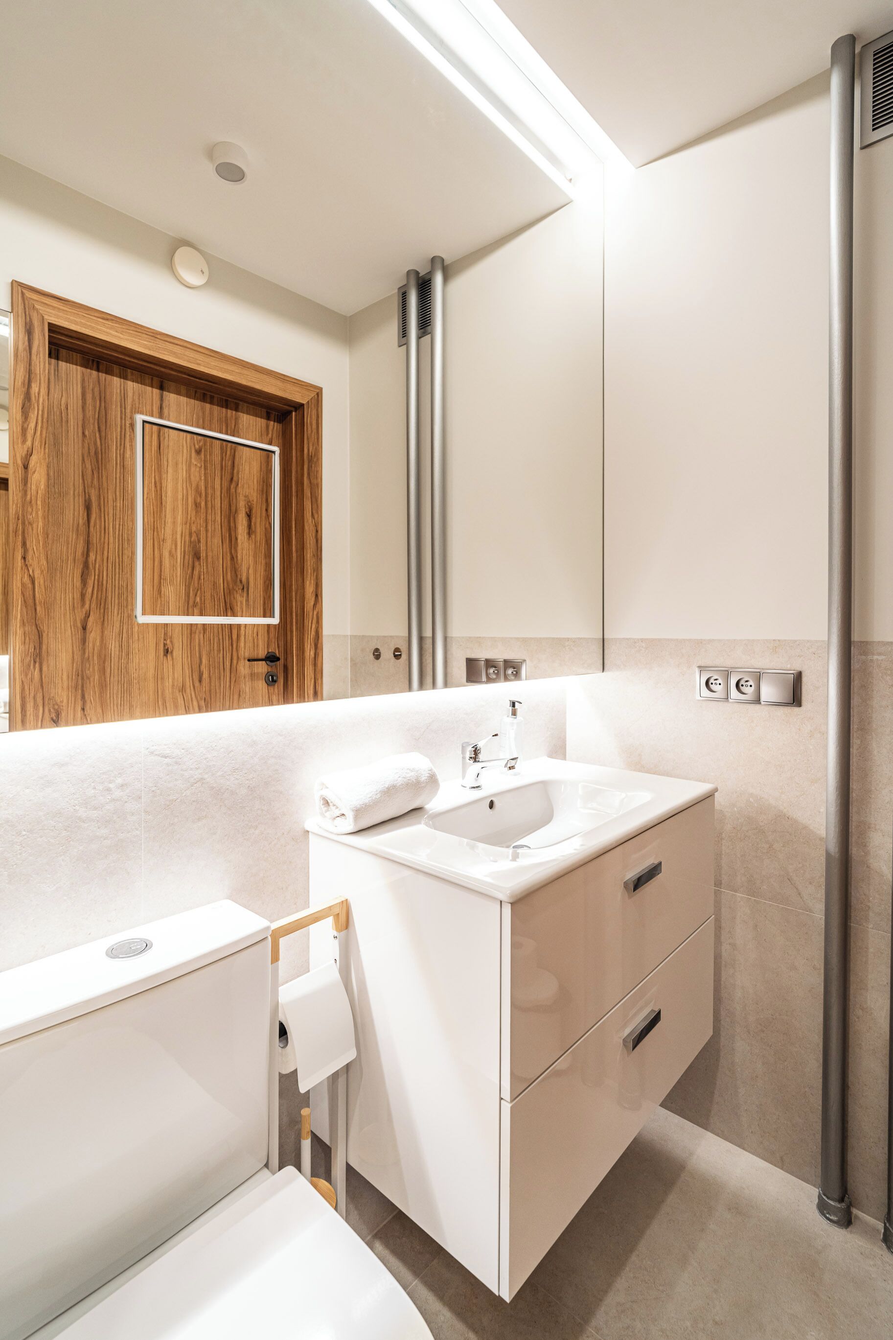 Et moderne badeværelse med en hvid kommode, et spejl, et håndklæde og et toilet.