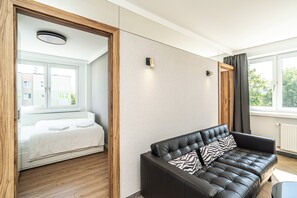 Habitación de hotel moderna con una cama, un sofá de cuero y vistas al exterior.