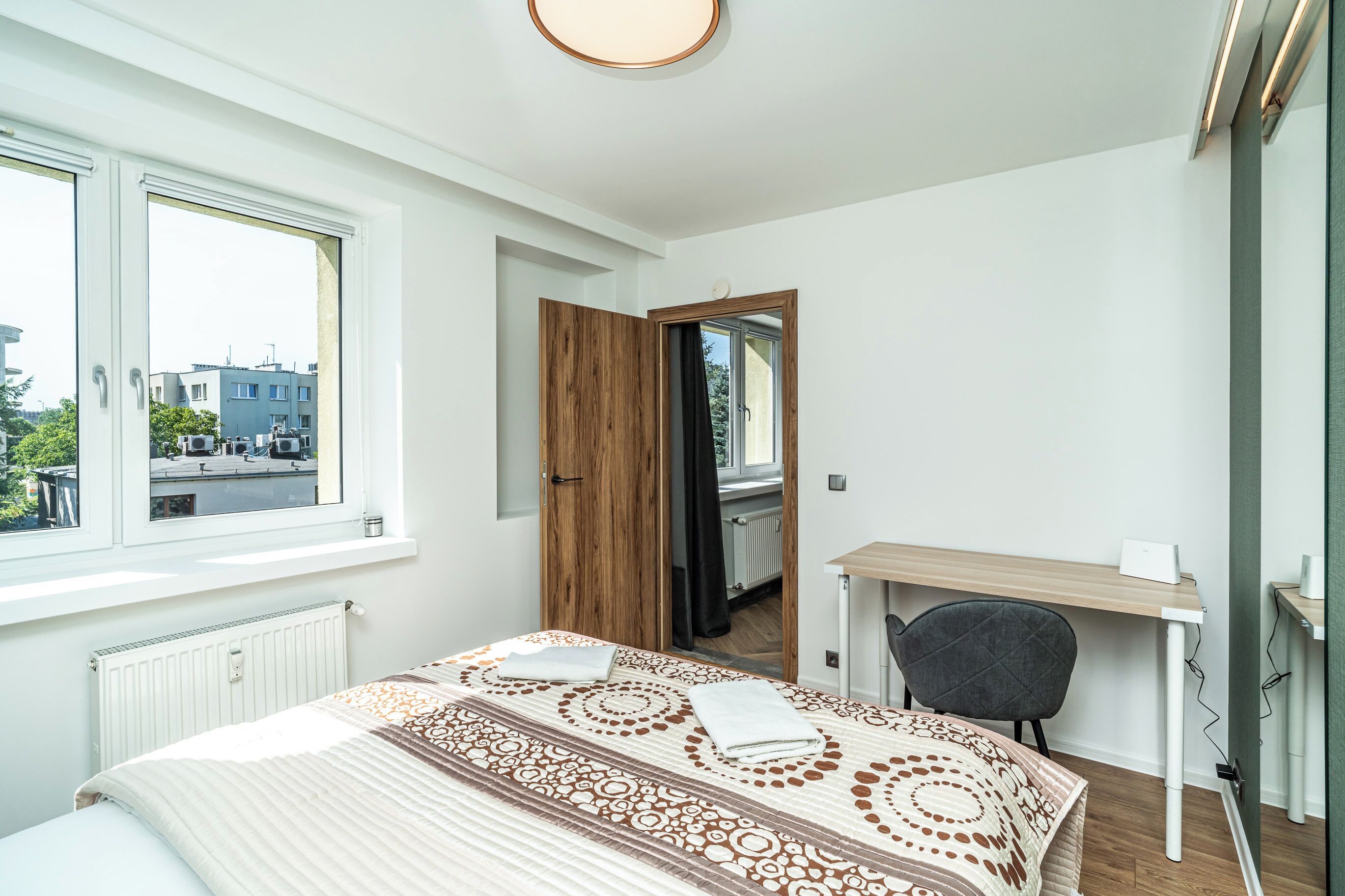Ein Schlafzimmer mit Bett, Schreibtisch, Stuhl und Fenster.
