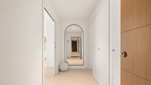 A hallway with a mirrored wall, a wooden door, and a round white object on the floor. - RDR577 - Designer 2-Bed with Garden in Camarate Hills (Buenas Noches)