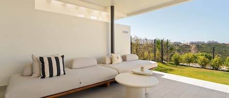 Una sala de estar moderna con un sofá, una mesita de centro y vistas a un paisaje verde.