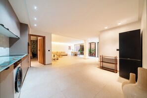 A spacious living area with a sofa, coffee table, and a dining table. There is a black cabinet and a wooden shelf unit. - Villa with Pool, Jacuzzi, Sauna, and Hammam in Marrakech (Marrakech)