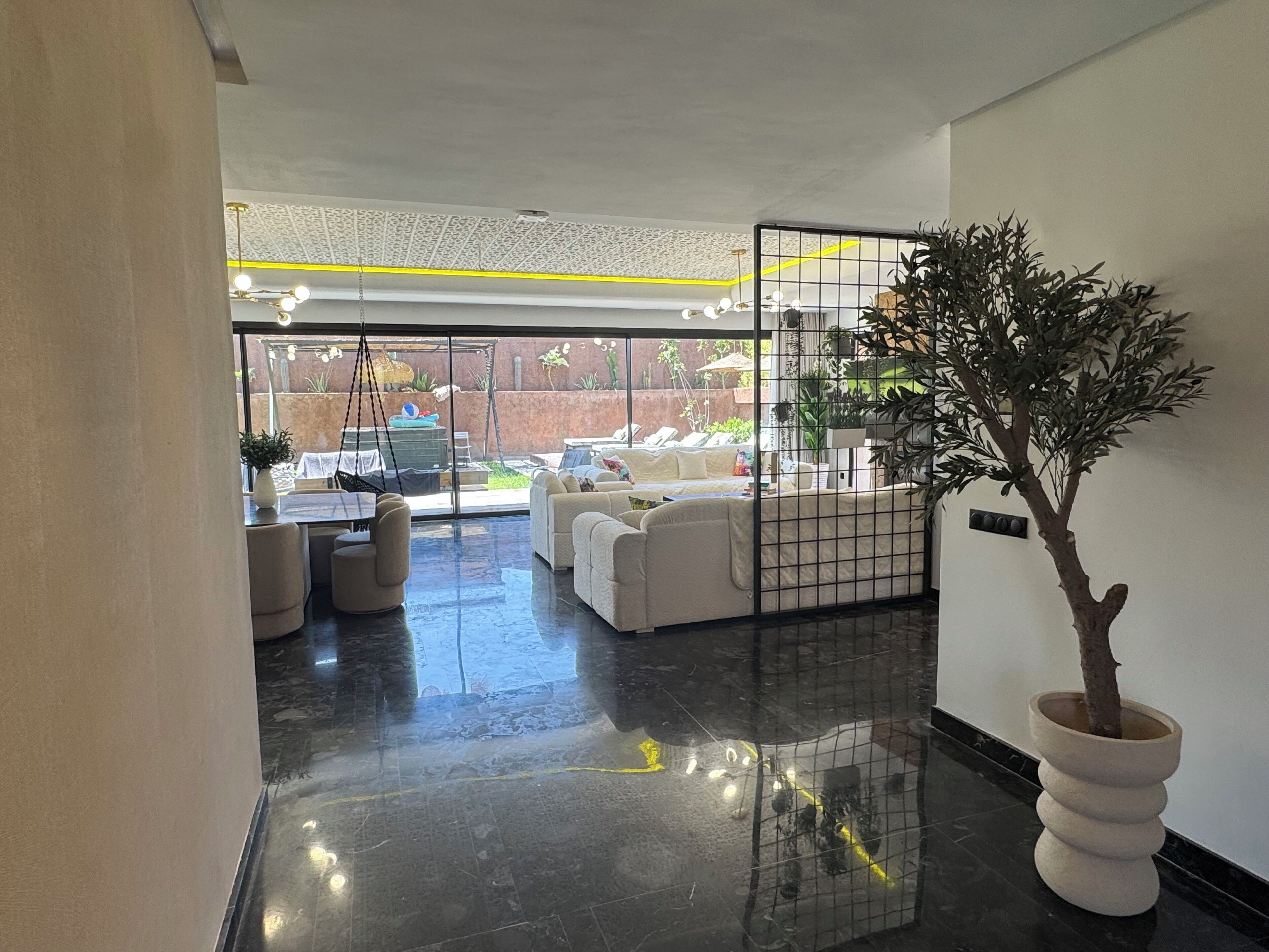 Un interior moderno con una zona de estar, una planta en maceta y vistas al exterior.