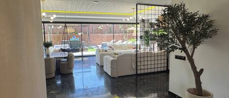 Un interior moderno con una zona de estar, una planta en maceta y vistas al exterior.