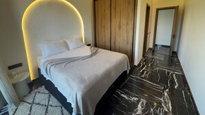 Een moderne slaapkamer met een gebogen hoofdeinde, een houten garderobe en een marmeren vloer.