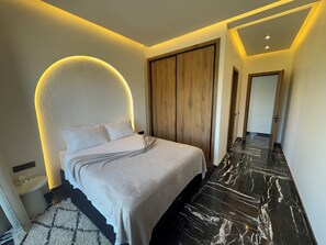 A modern bedroom with a curved headboard, a wooden wardrobe, and a marble floor. - Villa with Pool, Jacuzzi, Sauna, and Hammam in Marrakech (Marrakech)