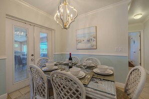 A dining room with a glass-top table, white chairs, and a chandelier. - Sleeps 8 - 2 bath- Pool and Hot Tub - Pet Friendly (Cape Coral)
