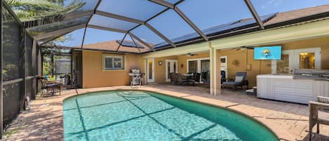 A covered swimming pool with a patio area, a barbecue grill, and outdoor seating.